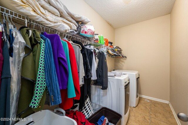 washroom with a textured ceiling, light tile patterned flooring, and washing machine and clothes dryer