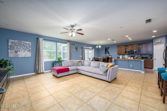 tiled living room with a textured ceiling and ceiling fan