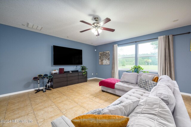 living room featuring a textured ceiling, ceiling fan, and tile patterned flooring