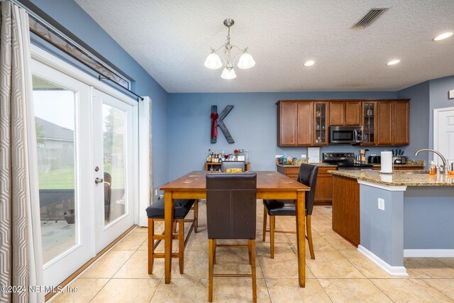 kitchen featuring pendant lighting, a textured ceiling, stainless steel appliances, and light stone countertops