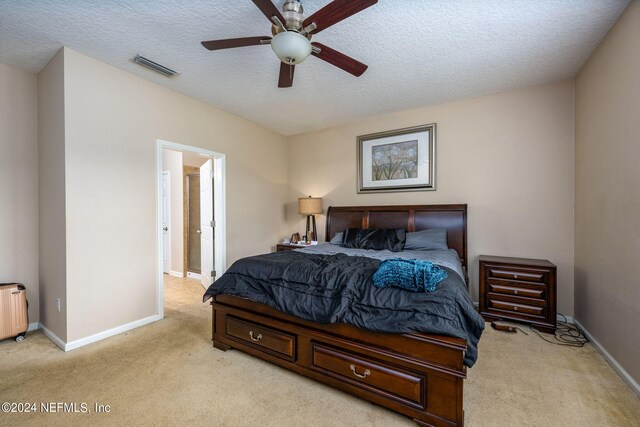 bedroom with light colored carpet, ceiling fan, and a textured ceiling