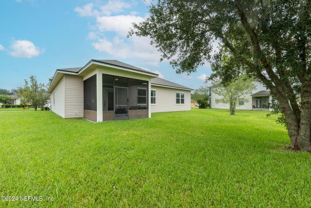 rear view of house featuring a sunroom and a lawn