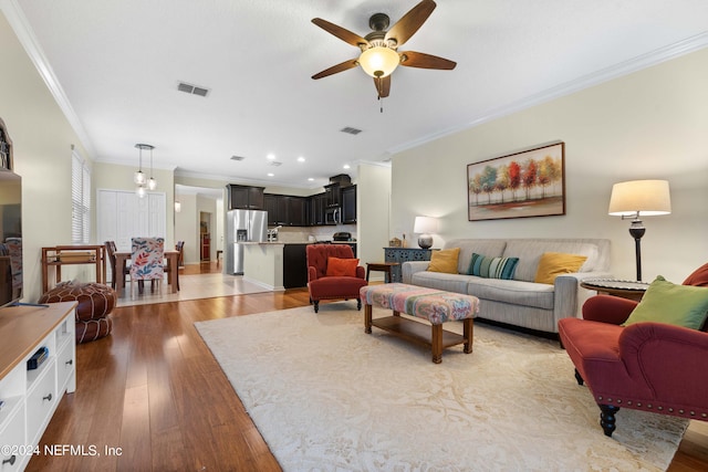 living room with ceiling fan, light wood-type flooring, and ornamental molding