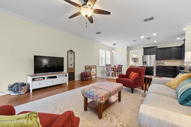 living room with hardwood / wood-style floors, ceiling fan, and crown molding