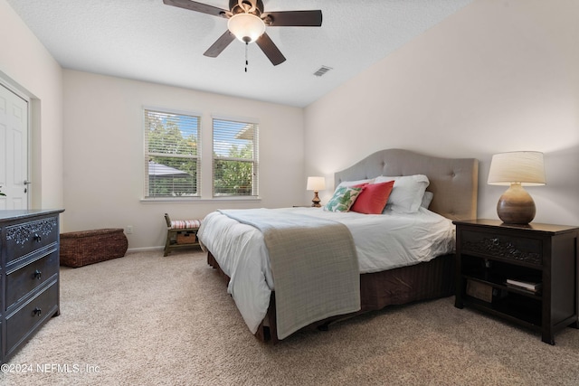 bedroom featuring ceiling fan, light colored carpet, and a textured ceiling