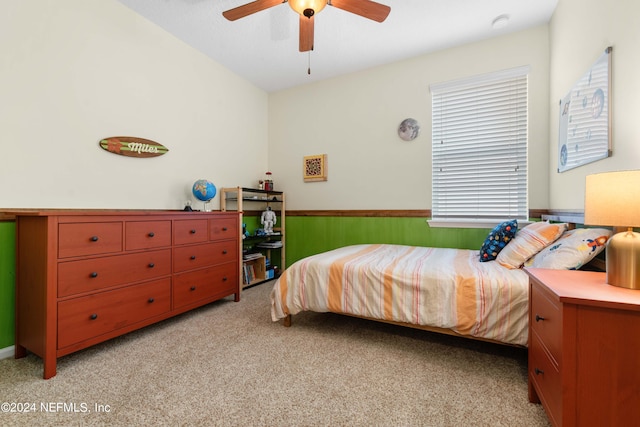 carpeted bedroom with ceiling fan and wood walls