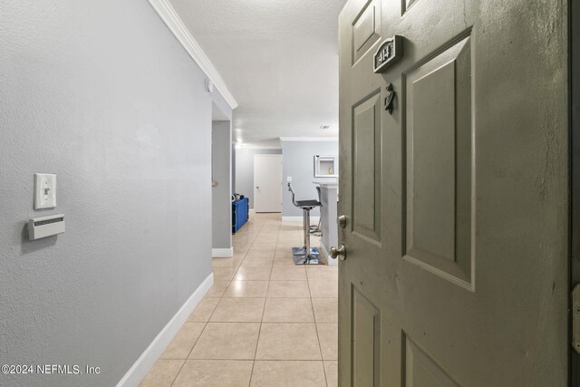 corridor featuring crown molding and light tile patterned flooring