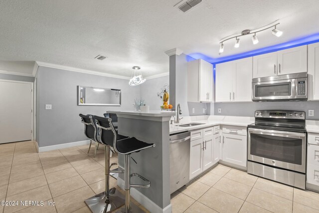 kitchen featuring ornamental molding, sink, appliances with stainless steel finishes, and white cabinetry