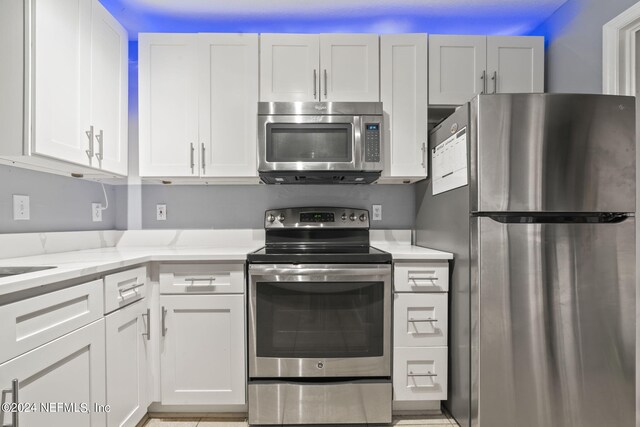 kitchen with white cabinetry, stainless steel appliances, and light stone countertops