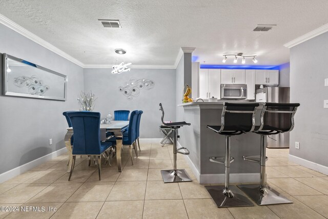 dining space featuring a textured ceiling, crown molding, and light tile patterned flooring