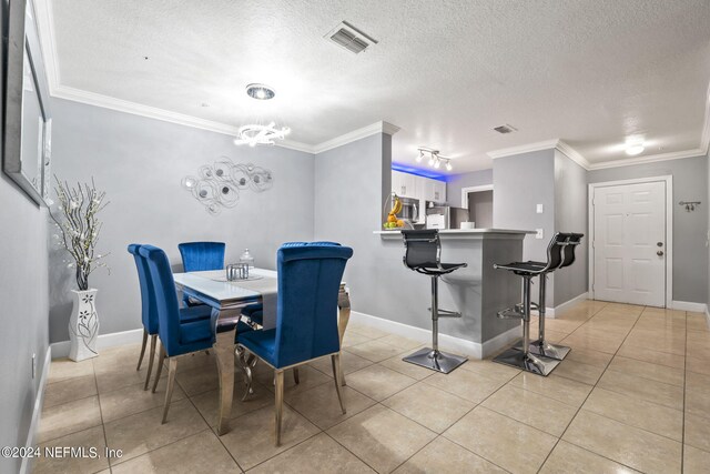 dining area with crown molding, a textured ceiling, and light tile patterned floors