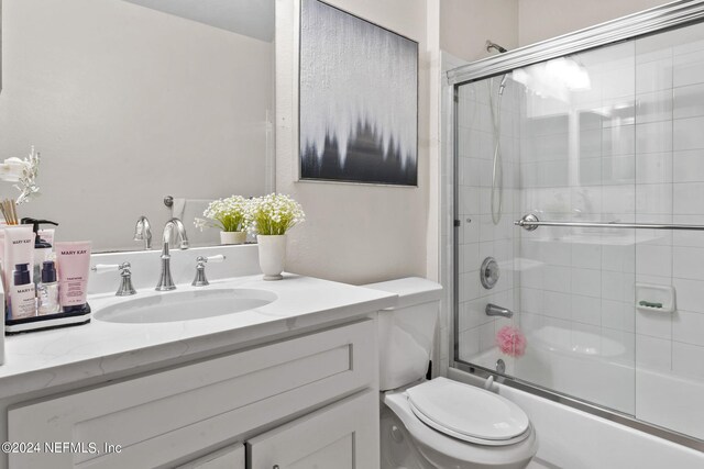 full bathroom with vanity, toilet, and bath / shower combo with glass door