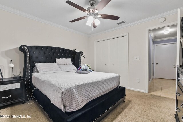 carpeted bedroom featuring crown molding, ceiling fan, and a closet