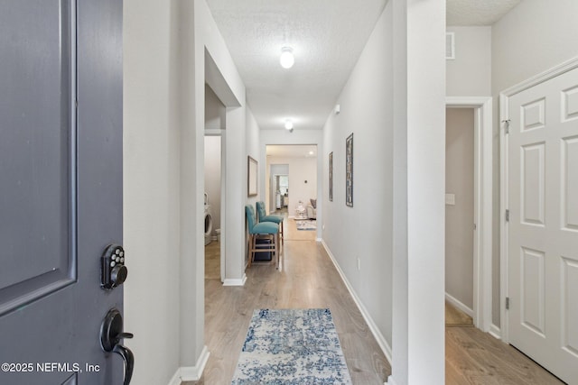 hall featuring a textured ceiling and light wood-type flooring