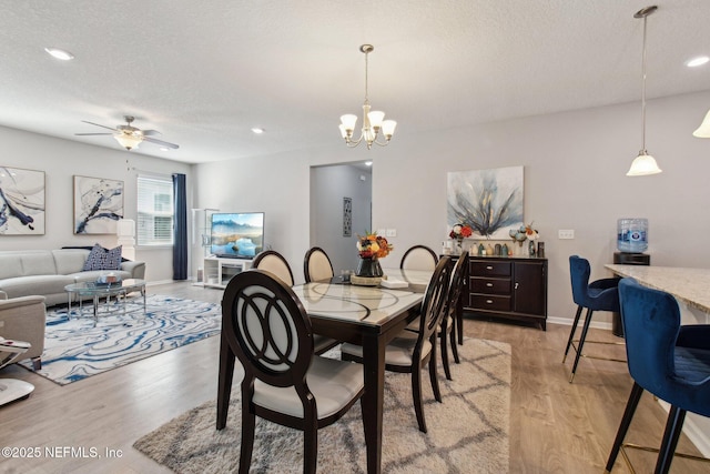 dining space featuring ceiling fan with notable chandelier, light hardwood / wood-style floors, and a textured ceiling