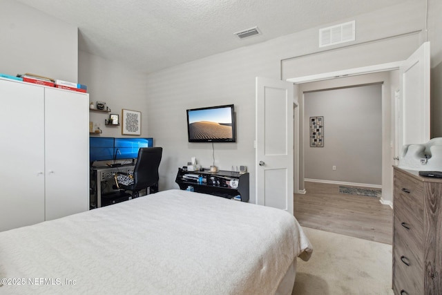 bedroom featuring light hardwood / wood-style flooring, a closet, and a textured ceiling