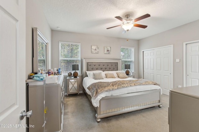 carpeted bedroom featuring ceiling fan and a textured ceiling