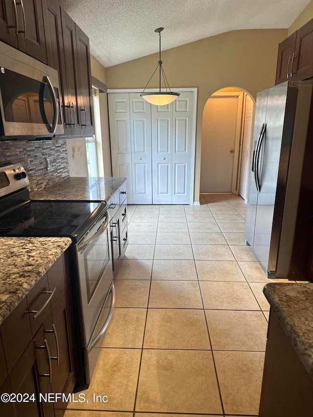 kitchen with light tile patterned floors, appliances with stainless steel finishes, lofted ceiling, dark brown cabinets, and decorative backsplash