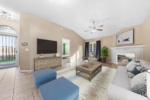 tiled living room with a tiled fireplace, vaulted ceiling, ceiling fan, and a textured ceiling