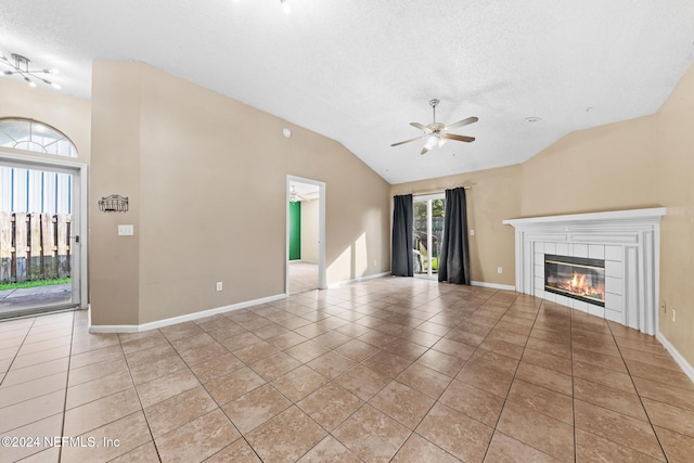 unfurnished living room with light tile patterned flooring, vaulted ceiling, a textured ceiling, and a fireplace