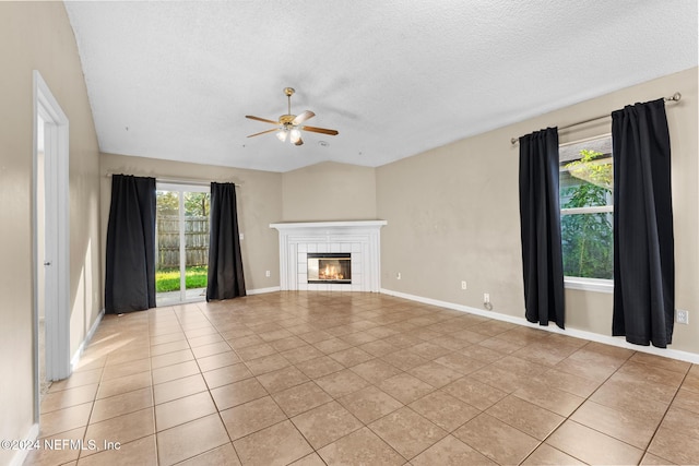 unfurnished living room with ceiling fan, a textured ceiling, a tile fireplace, and light tile patterned floors