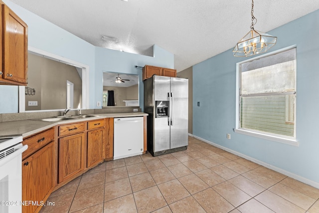 kitchen featuring light tile patterned flooring, sink, hanging light fixtures, a textured ceiling, and white appliances