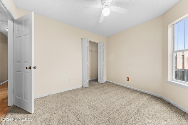 unfurnished bedroom with multiple windows, carpet floors, and a textured ceiling