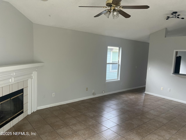 unfurnished living room with dark tile patterned flooring, a tile fireplace, and ceiling fan