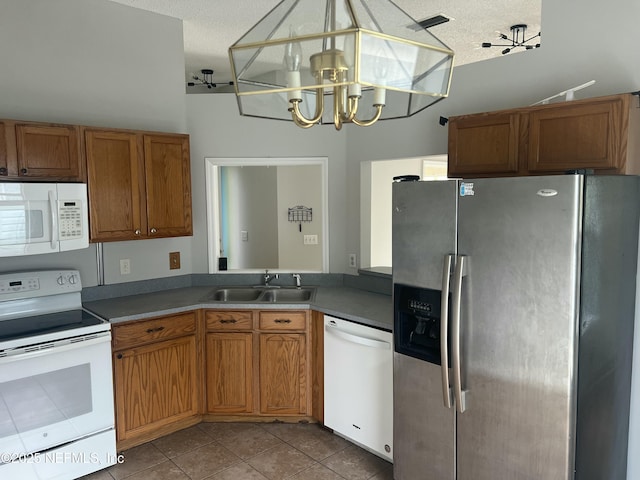 kitchen featuring sink, a textured ceiling, light tile patterned floors, pendant lighting, and white appliances