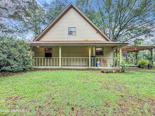 rear view of house featuring a porch and a lawn