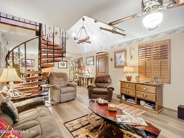 living room with ceiling fan with notable chandelier, light hardwood / wood-style flooring, and a textured ceiling