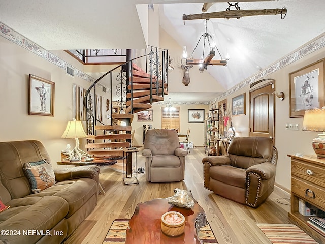 living room featuring lofted ceiling, a notable chandelier, light hardwood / wood-style floors, and a textured ceiling