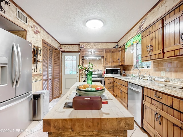 kitchen featuring stainless steel appliances, crown molding, a kitchen island, and sink