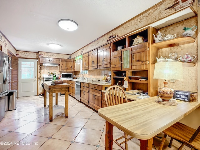 kitchen with light tile patterned flooring, sink, crown molding, a textured ceiling, and stainless steel appliances