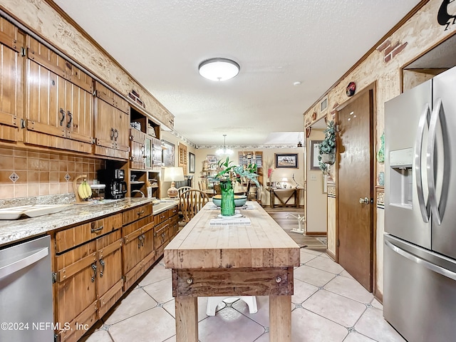 kitchen with stainless steel appliances, a kitchen island, light tile patterned floors, and a textured ceiling