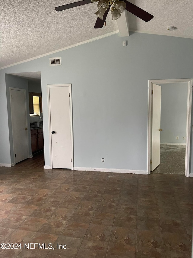 unfurnished room featuring ceiling fan, vaulted ceiling with beams, and a textured ceiling