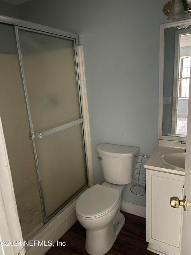 bathroom with hardwood / wood-style floors, vanity, a shower with shower door, and toilet