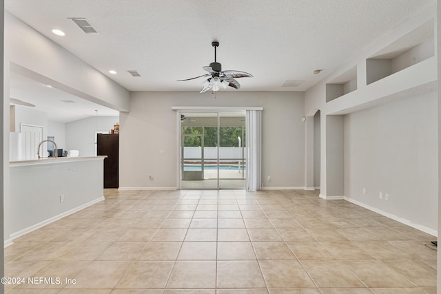 interior space with ceiling fan, a textured ceiling, and light tile patterned floors