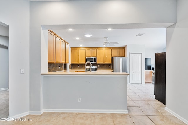 kitchen with ceiling fan, light brown cabinets, light tile patterned flooring, backsplash, and appliances with stainless steel finishes