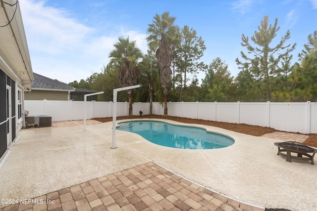 view of swimming pool featuring central AC unit, a fire pit, and a patio area