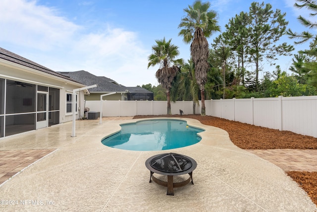 view of swimming pool with central AC, a sunroom, an outdoor fire pit, and a patio area