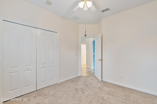 unfurnished bedroom featuring light carpet, a closet, and ceiling fan