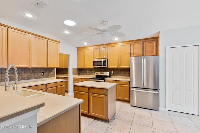 kitchen with light tile patterned floors, stainless steel appliances, a center island, ceiling fan, and sink