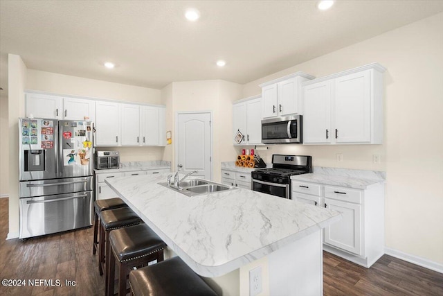 kitchen featuring appliances with stainless steel finishes, white cabinetry, dark hardwood / wood-style flooring, a center island with sink, and sink