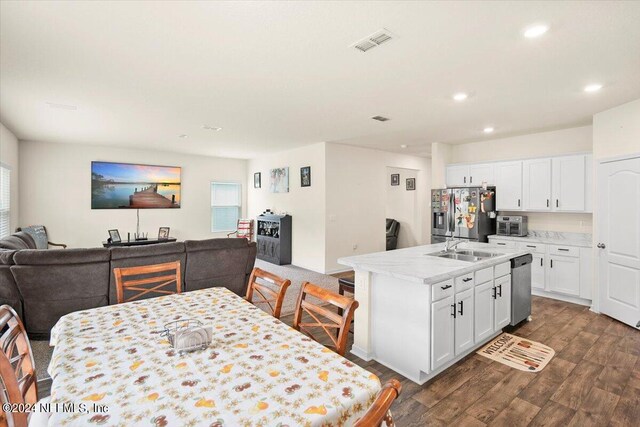 kitchen with white cabinets, an island with sink, sink, stainless steel appliances, and dark hardwood / wood-style flooring