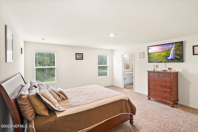 carpeted bedroom featuring connected bathroom, multiple windows, and a textured ceiling