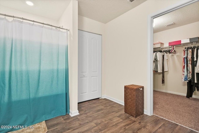 unfurnished bedroom with a textured ceiling, dark wood-type flooring, and a closet