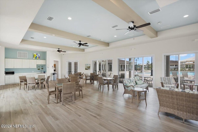 living room with ceiling fan, beamed ceiling, and light hardwood / wood-style flooring