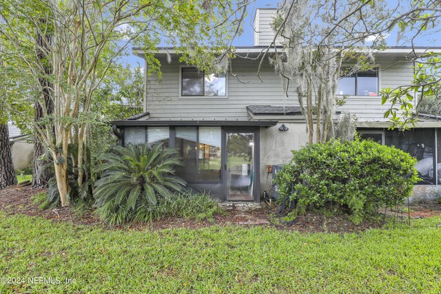 rear view of property with a sunroom and a lawn