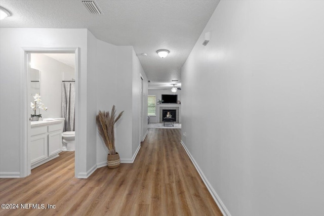 corridor with a textured ceiling and light hardwood / wood-style flooring